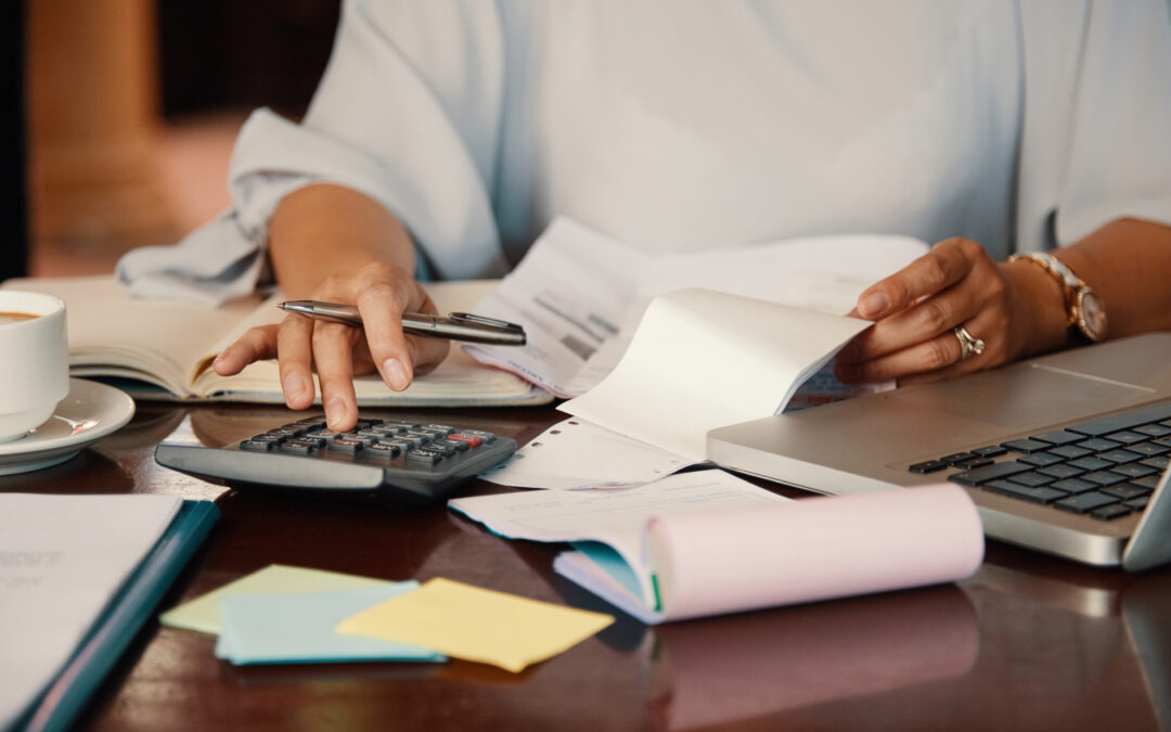 CPA is doing tax calculations with the help of a laptop and calculator.