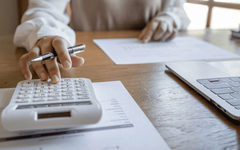 The accountant is doing tax calculations with the help of a laptop and calculator.